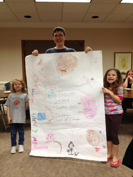 Andrew Pfaff ('12) poses with some local Girl Scouts and their "thank you card" from the Order of Omega Girl Scout Cookie Drive