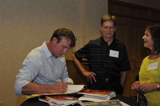 DePauw Professor Joe Haithaus (left) signing his books for alumni Jim Fisher '68 and Kathy Wildt '75 following poetry reading at the "Living with Joy" retreat