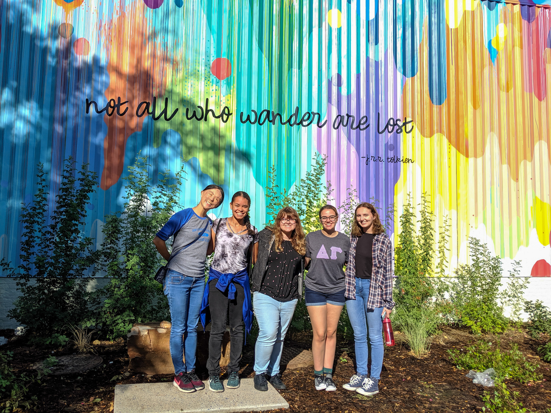 students standing nexto to building with mural on it