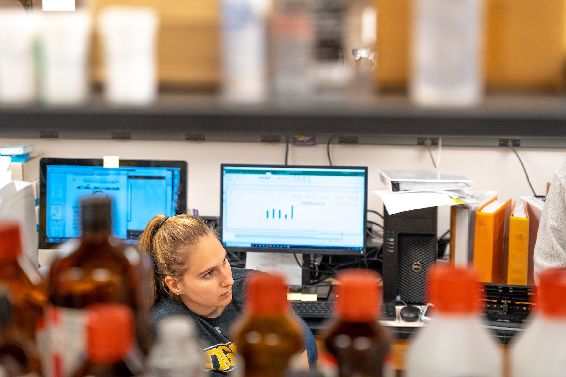 Student sitting behind some bottles during summer research 