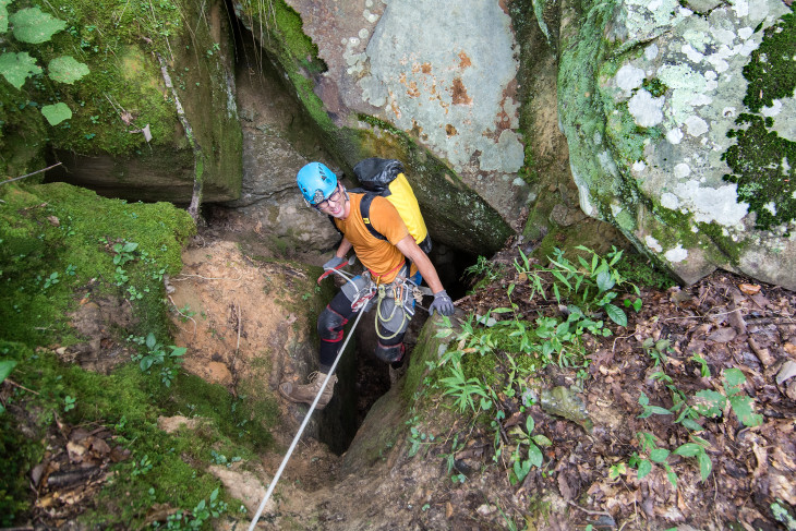 Philip Rykwalder enters a cave through a tiny hole on the surface