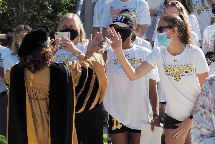 Dr. White high-fives students at her inauguration.