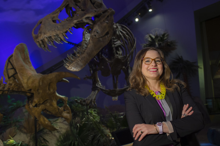 Jennifer Pace Robinson stands in front of dinosaur skeleton.