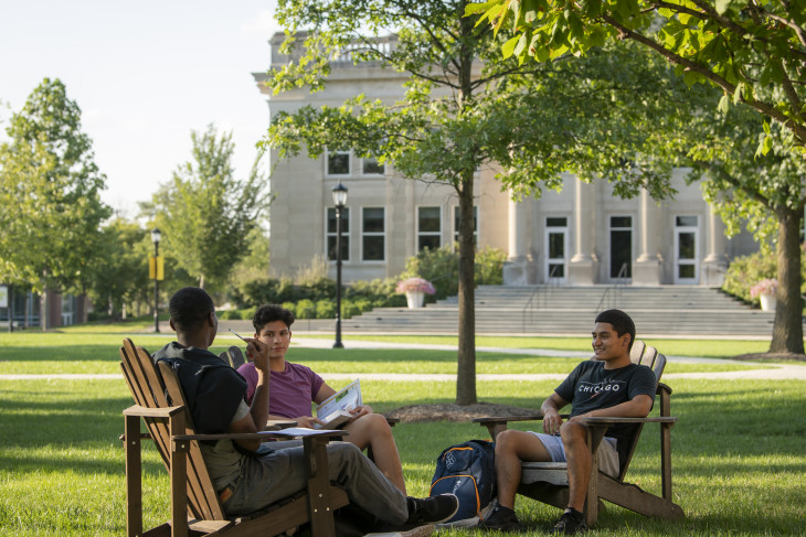 Students sitting on the East College lawn with Emison building in the background
