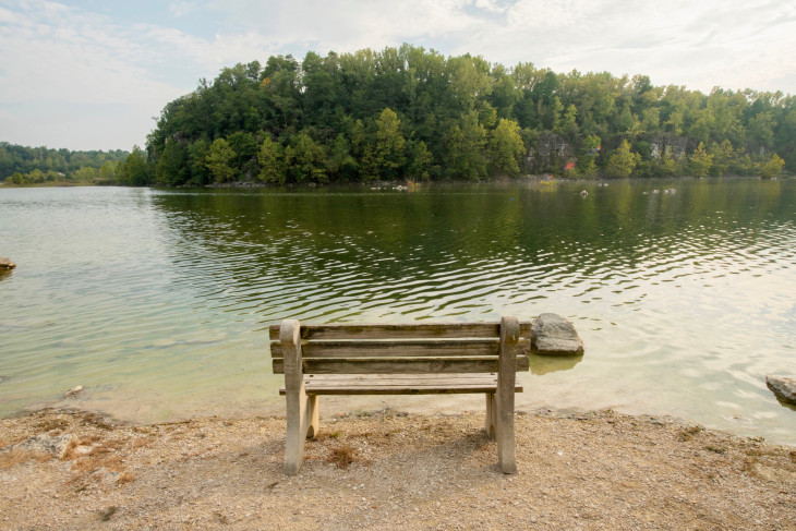 An empty bench in front of an expanse of water in the DePauw Nature Park