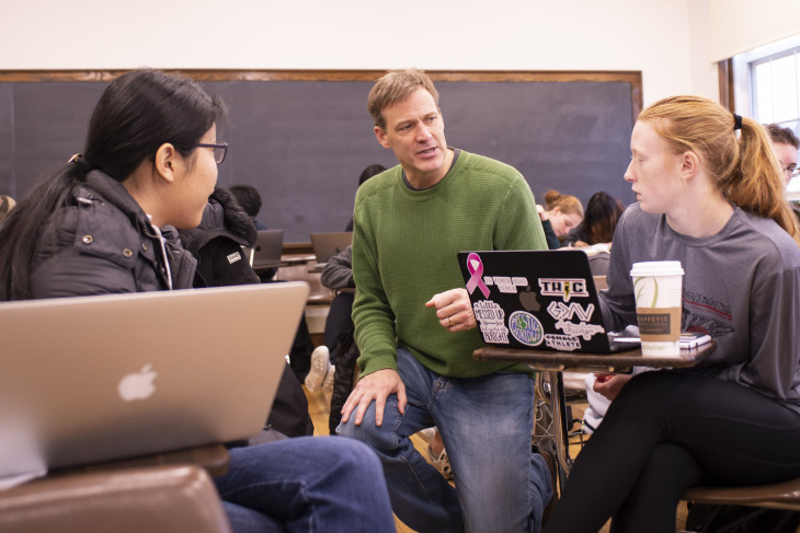 Professor in the classroom with two students. 