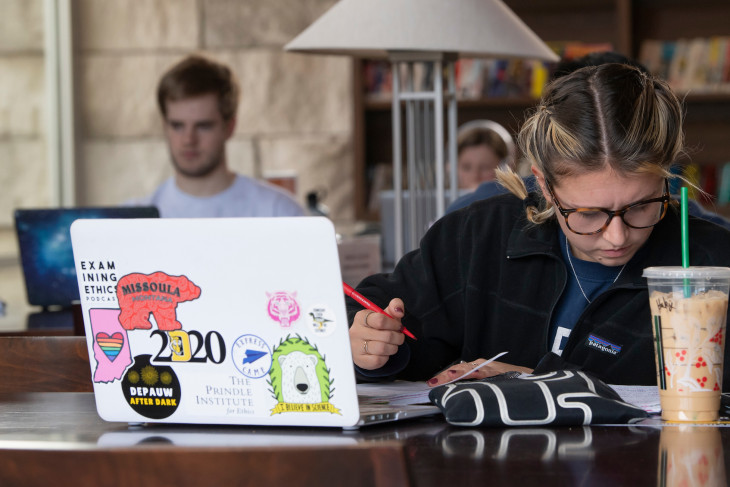 student sitting at a table with a coffee and a computer