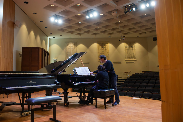 Musician Bright Sheng at a piano with a student 