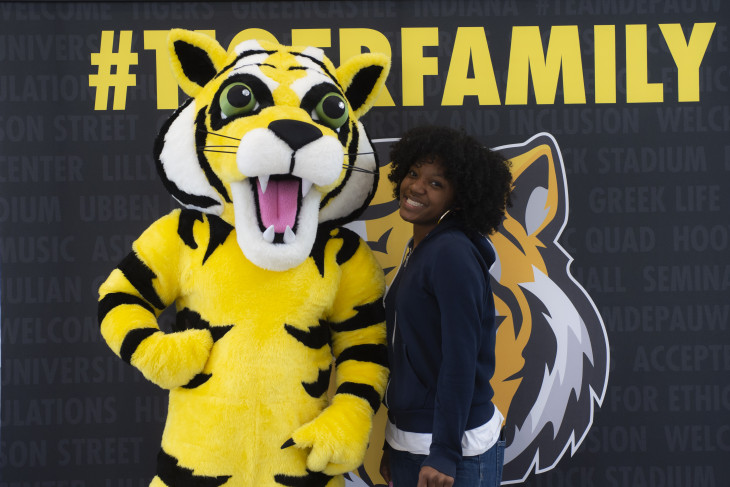 student and tyler the tiger stand in front of a sig