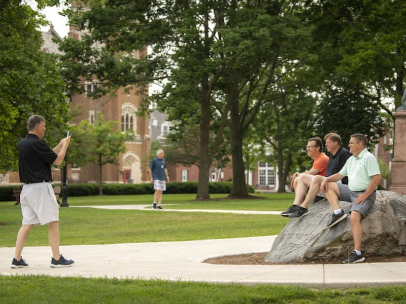 Alumni taking photos by the boulder