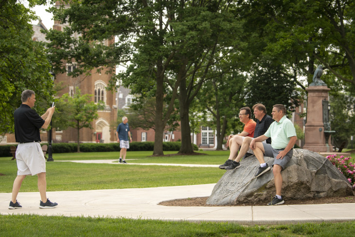 Alumni taking photos by the boulder