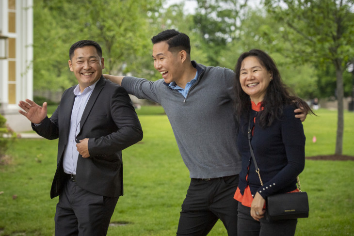 three people laughing and smiling while walking on campus