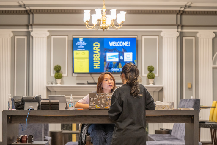 A student helps another in the Hubbard Center Lobby