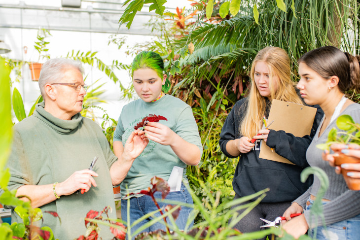 Professor in greenhouse with students