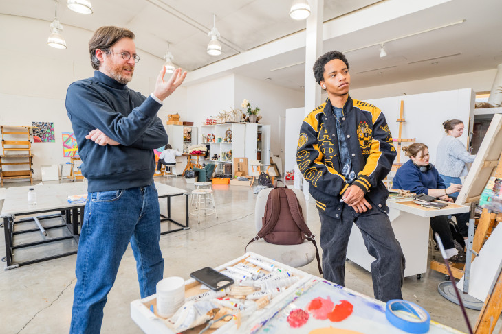 Faculty and student reviewing a painting