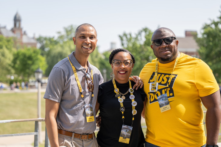 3 Alumni smiling together on campus