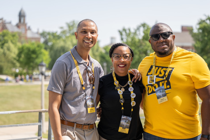 3 Alumni smiling together on campus