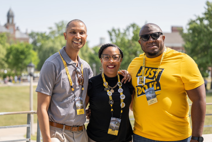 3 Alumni smiling together on campus