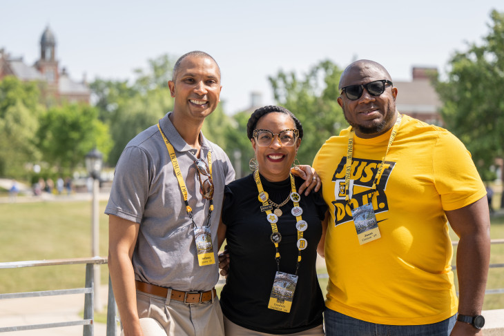 3 Alumni smiling together on campus