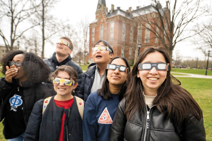 Students in eclipse glasses look to the sky