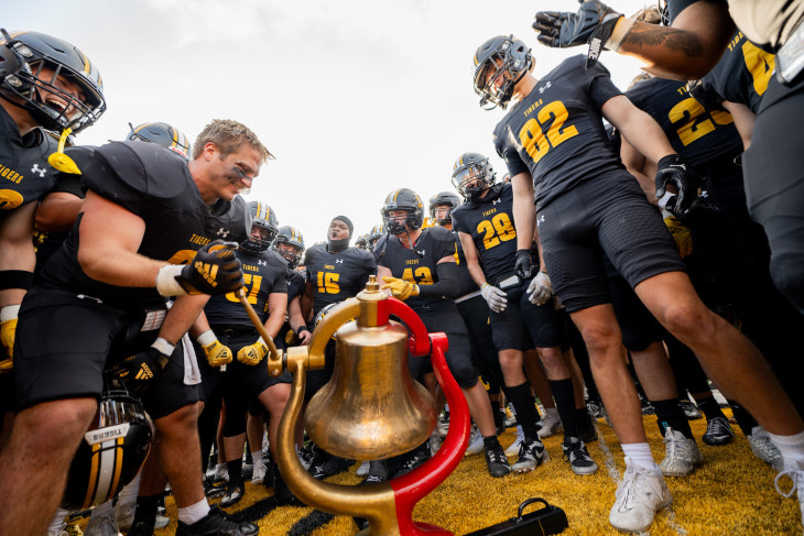 DePauw football players gather around the Monon Bell