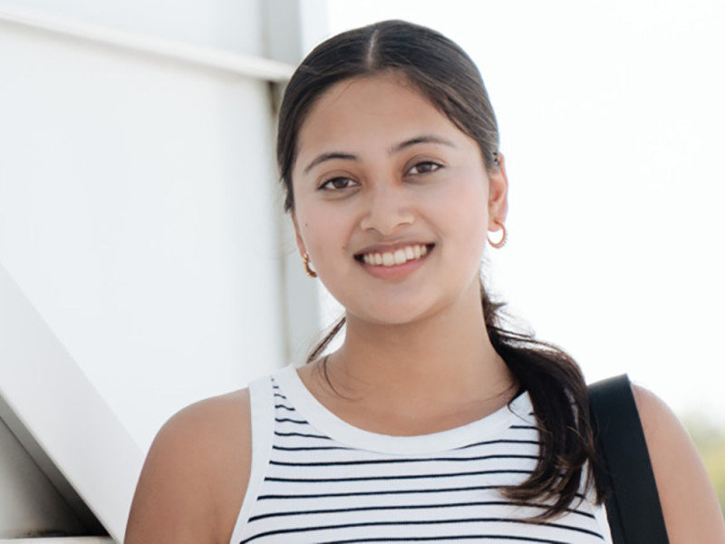 female posing for camera with white shirt and bag