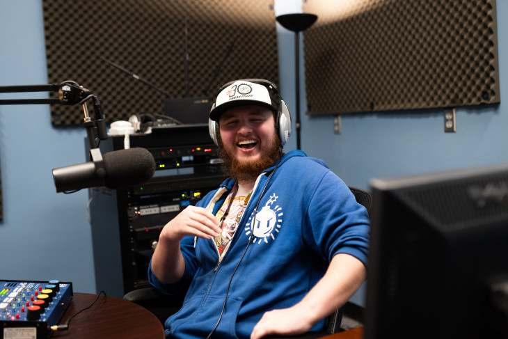 Student laughs on microphone in podcast studio