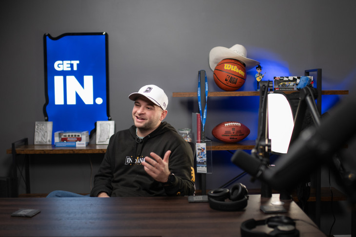 Nate Spangle sitting in front of Get Indiana sign at desk 