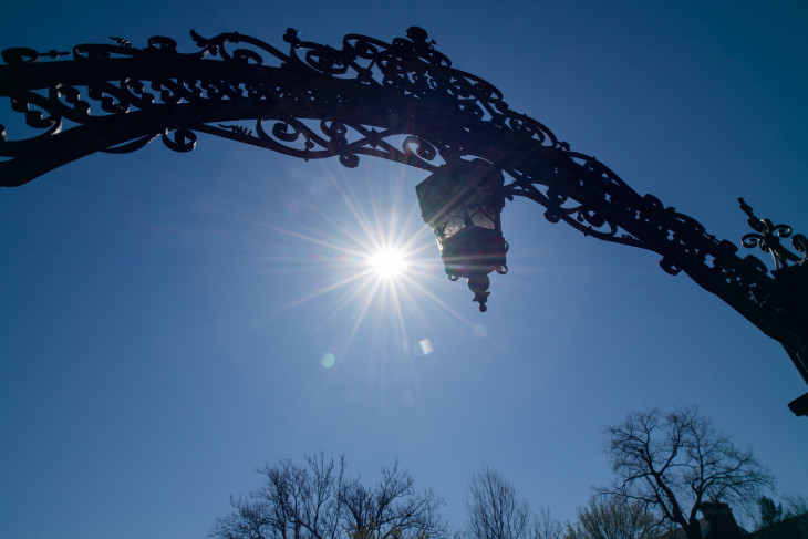 The sun glistens behind the arch. 