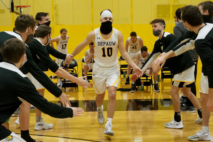 Masked basketball player runs into the game, greeted by teammates