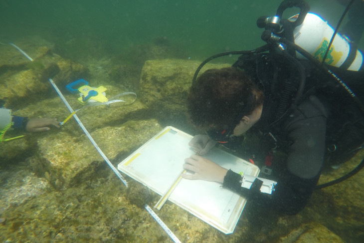 Caleb underwater marking on a white board and making measurements