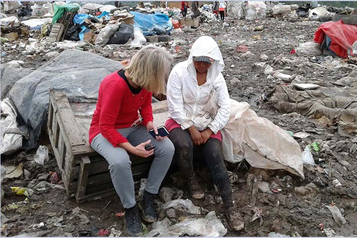 Betsy Hake seated beside a woman within debris