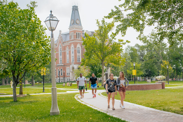 Three staff members cheering in front of East College