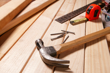 Hammer and measuring tape sitting on wood boards