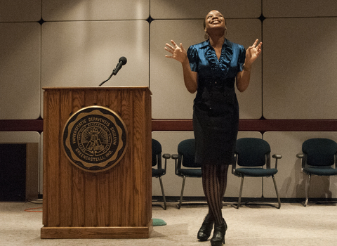 Chinonye Chukwu '07 standing next to a podium speaking to a DePauw audience