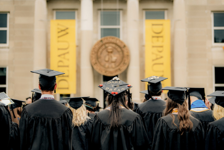 Commencement day students with cap and gown on in front of DePauw lawn