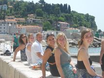 Students sitting on a concrete block along the water looking over their shoulders