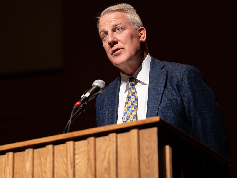male in suit speaking at podium