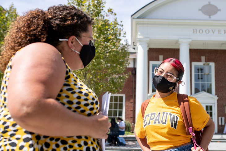 Masked student and staffer talk outside 