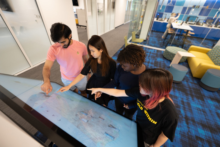 Four students using a touch screen in the library's Tenzer space