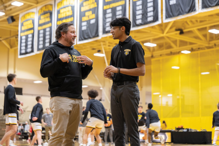 Student and alum talk at a basketball game