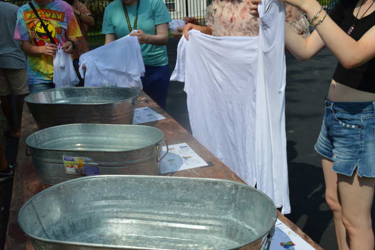 Group of students holding white shirts, in the process of tye-dying