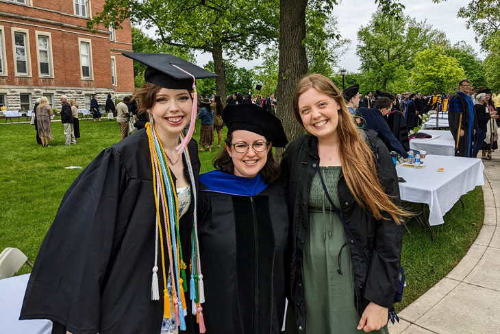 Three people smiling in college graduation attire