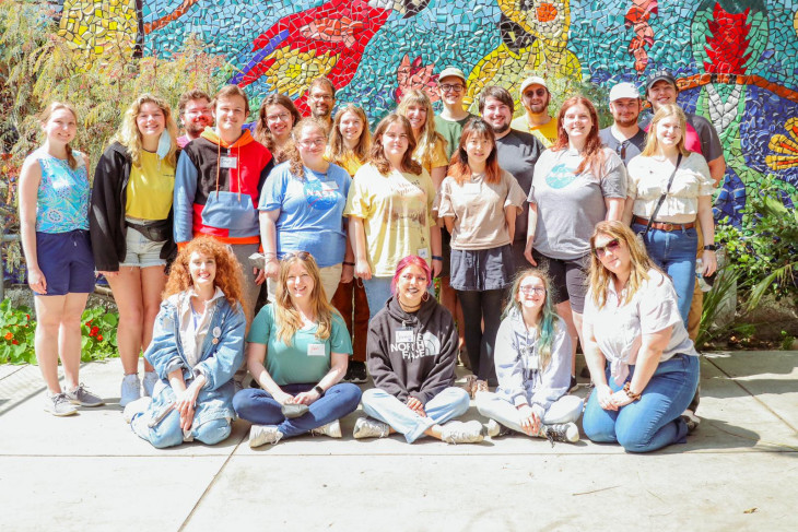 Group of people in colorful outfits against a playful wall