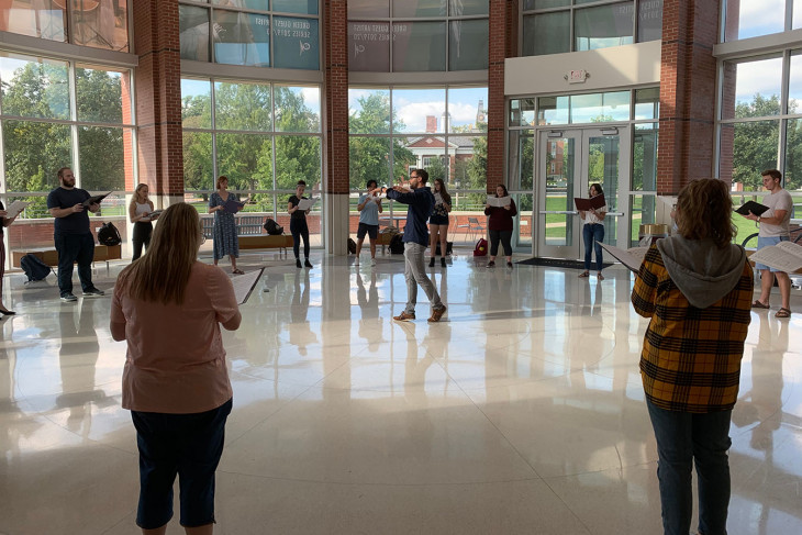 Choir singing in a circle with a conductor in the center