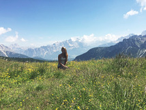 Scenic photo of a student standing in a field of flowers with mountains in the background