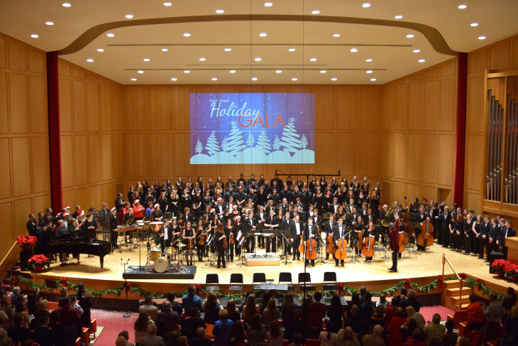 Orchestra and choir on stage with holiday decorations
