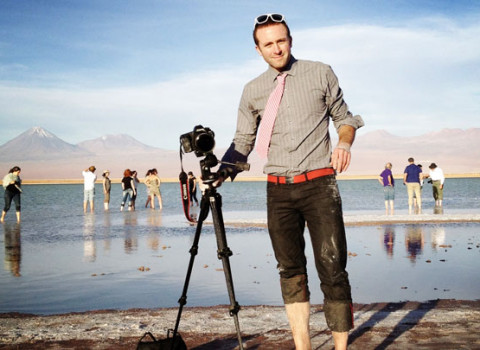 Ian Cheney with his camera amongst a scenic water and mountain background