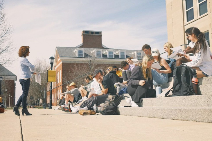 Professor Francesca Seaman teaching a class outside on the steps of the admissions building.