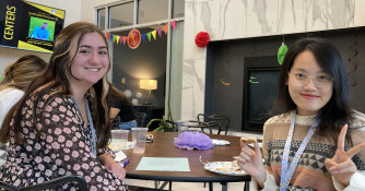 Two students smiling while sitting at a table